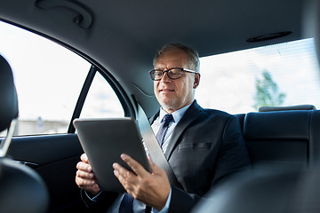 Image showing senior businessman with tablet pc driving in car