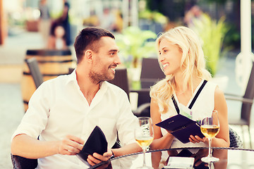 Image showing happy couple with wallet paying bill at restaurant