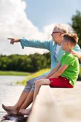 Image showing grandfather and grandson sitting on river berth