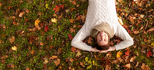 Image showing smiling young man lying on ground in autumn park