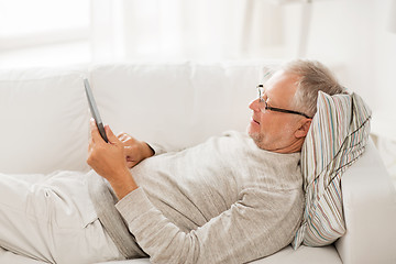 Image showing senior man with tablet pc lying on sofa at home