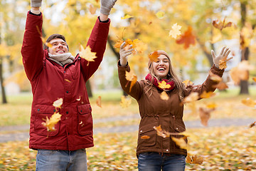 Image showing happy young couple throwing autumn leaves in park