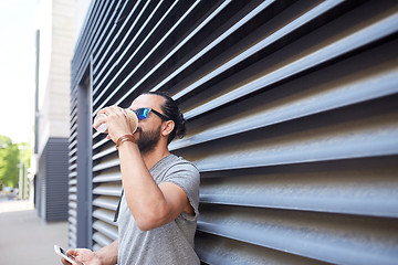 Image showing man with smartphone drinking coffee on city street