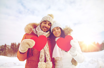 Image showing happy couple with red hearts over winter landscape