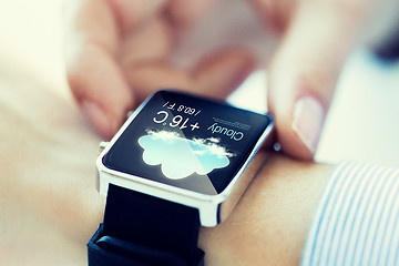 Image showing close up of hands with weather icon on smartwatch