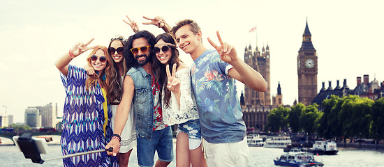 Image showing smiling hippie friends with selfie stick in london