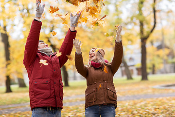 Image showing happy young couple throwing autumn leaves in park