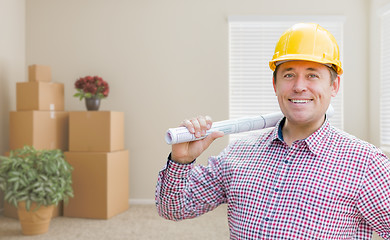 Image showing Male Construction Worker In Room With Boxes Holding Roll of Blue