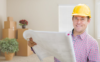 Image showing Male Construction Worker In Room With Boxes Holding Roll of Blue