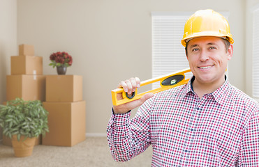 Image showing Male Construction Worker In Room With Moving Boxes Holding Level