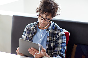 Image showing man with tablet pc and earphones sitting at cafe