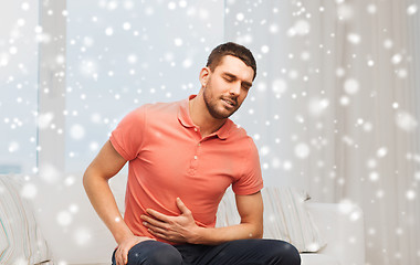 Image showing unhappy man suffering from stomach ache at home