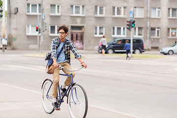 Image showing young hipster man with bag riding fixed gear bike