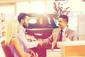 Image showing happy couple with car dealer in auto show or salon