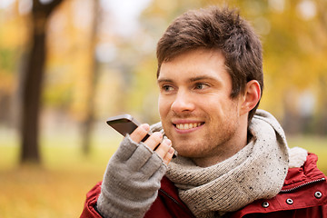 Image showing man recording voice on smartphone at autumn park