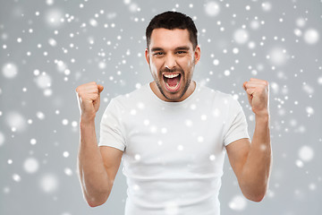 Image showing angry young man holding fists over snow