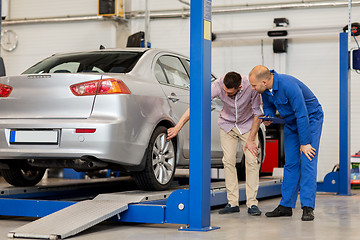 Image showing auto mechanic with clipboard and man at car shop