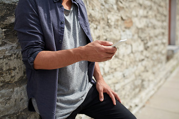 Image showing close up of man with smartphone at stone wall