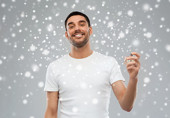 Image showing smiling man with male perfume over snow background