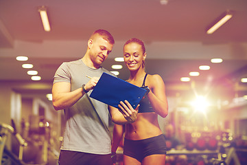 Image showing smiling young woman with personal trainer in gym