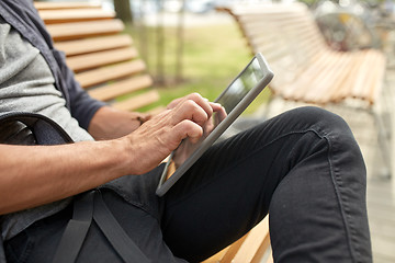 Image showing close up of man with tablet pc sitting on bench