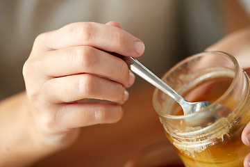 Image showing close up of woman hands with honey and spoon