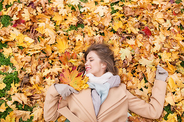 Image showing beautiful happy woman lying on autumn leaves