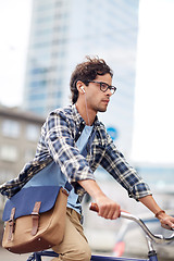 Image showing young hipster man with bag riding fixed gear bike