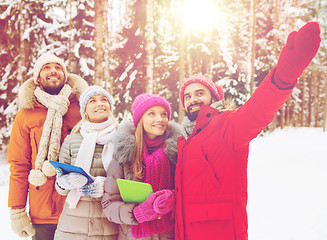 Image showing smiling friends with tablet pc in winter forest