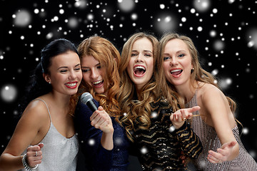 Image showing happy young women with microphone singing karaoke