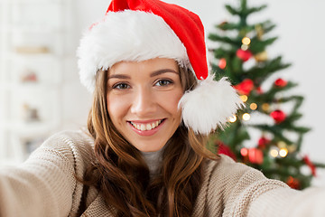 Image showing happy woman taking selfie over christmas tree