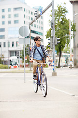 Image showing young hipster man with bag riding fixed gear bike