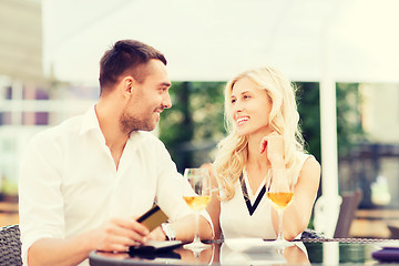 Image showing happy couple with bank card and bill at restaurant