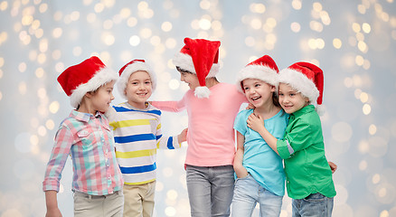 Image showing happy little children in santa hats hugging