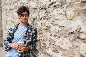 Image showing man in eyeglasses drinking coffee over street wall