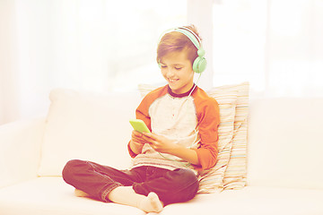 Image showing happy boy with smartphone and headphones at home