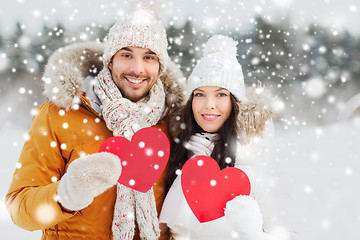 Image showing happy couple with red hearts over winter landscape