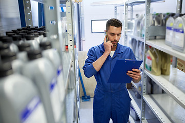 Image showing auto mechanic calling on smartphone at car shop