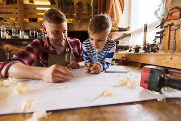 Image showing happy father and son with blueprint at workshop