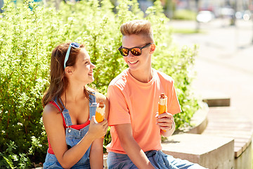 Image showing happy teenage couple eating hot dogs in city