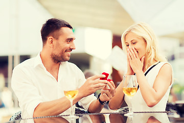 Image showing happy couple with engagement ring and wine at cafe