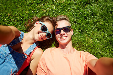 Image showing happy teenage couple taking selfie on summer grass