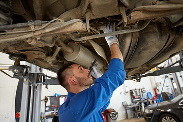 Image showing mechanic man with flashlight repairing car at shop