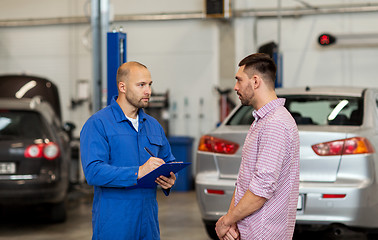 Image showing auto mechanic with clipboard and man at car shop