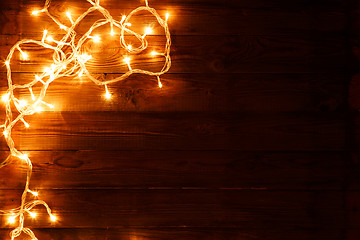 Image showing Dark brown wooden background with shining garland on the left