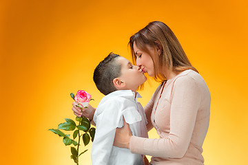 Image showing Young kid giving red rose to his mom