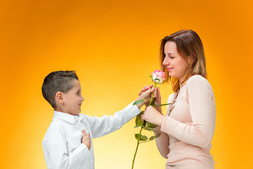 Image showing Young kid giving red rose to his mom