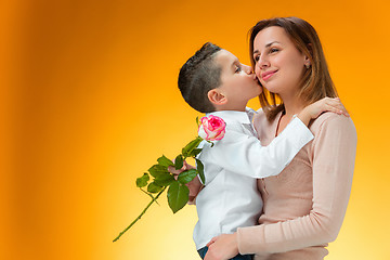 Image showing Young kid giving red rose to his mom