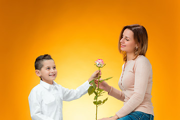 Image showing Young kid giving red rose to his mom