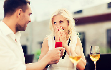 Image showing happy couple with engagement ring and wine at cafe
